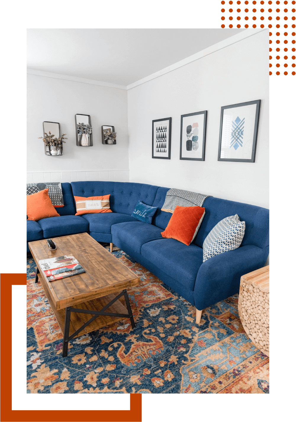A living room with blue couches and orange pillows.