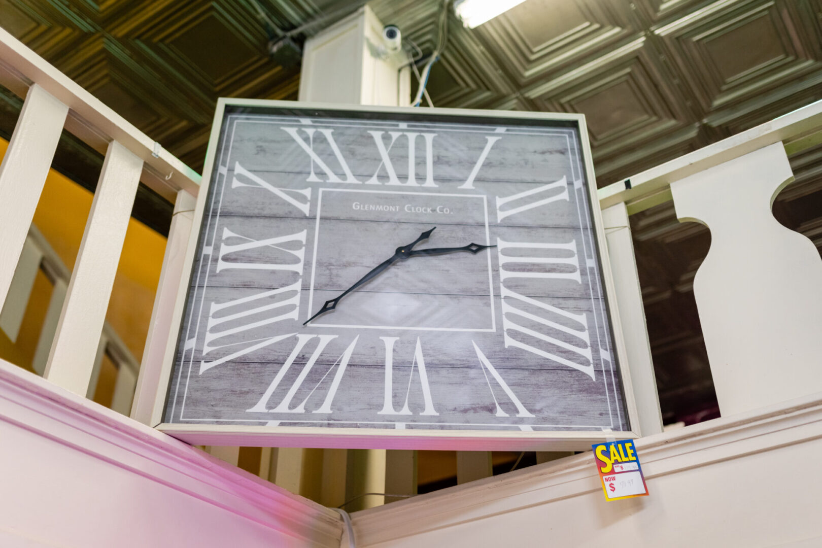 A large clock hanging from the ceiling of a store.