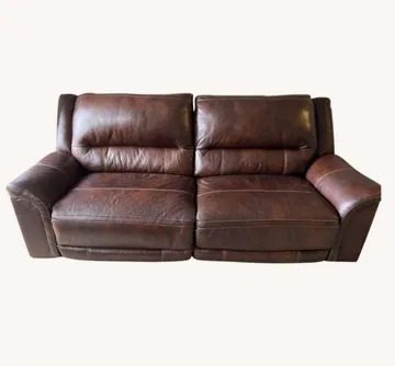 A brown leather couch with two recliners on top of it.